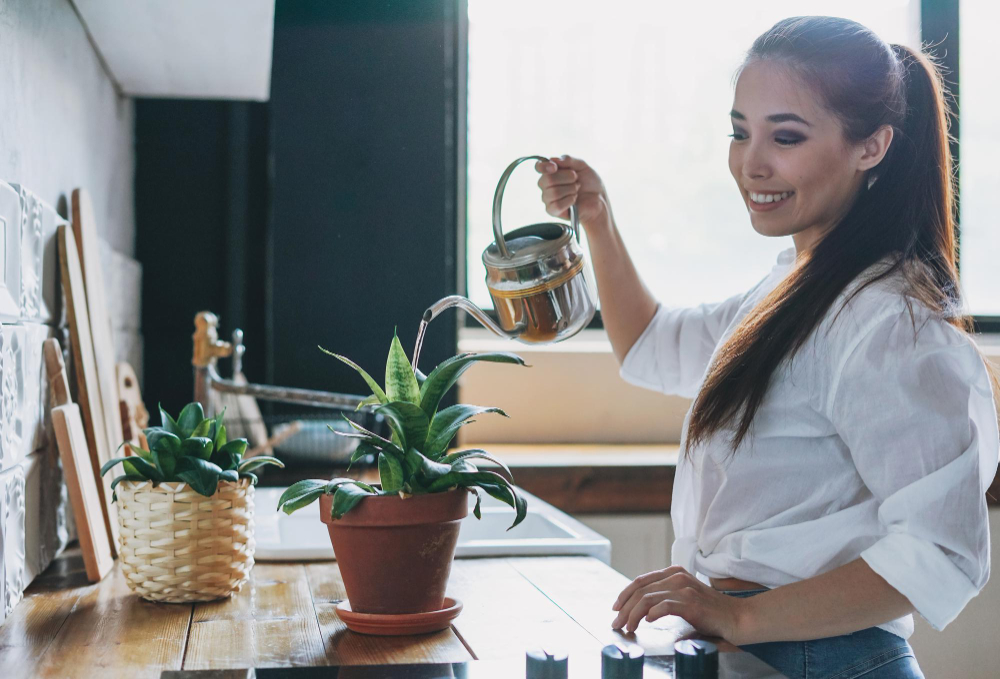 joven mujer asiatica sonriente ropa informal regando plantas interior cocina